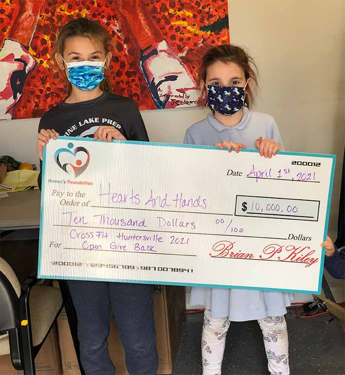 Two young girls holding a check to hearts and hands for 10k